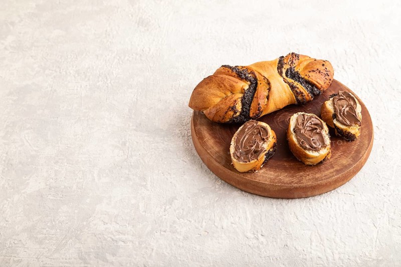 Homemade sweet bun with chocolate cream on a gray concrete background. side view, copy space