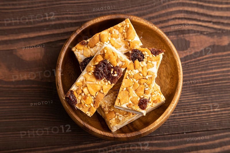 Traditional candy nougat with nuts and sesame on brown wooden background. top view, flat lay, close up