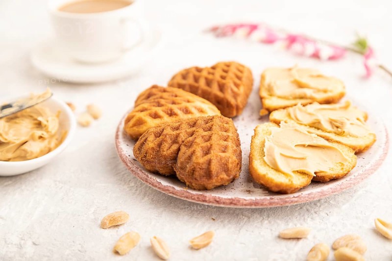 Homemade waffle with peanut butter and cup of coffee on a gray concrete background. side view, close up, selective focus