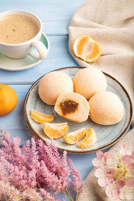Japanese rice sweet buns mochi filled with tangerine jam and cup of coffee on a blue wooden background and linen textile. side view, close up