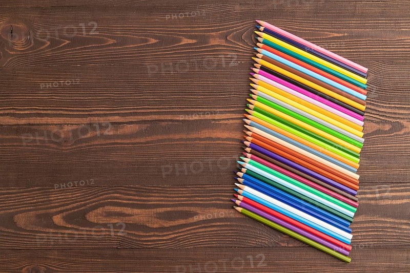 Set of watercolor pencils on brown wooden background. Top view, flat lay, copy space