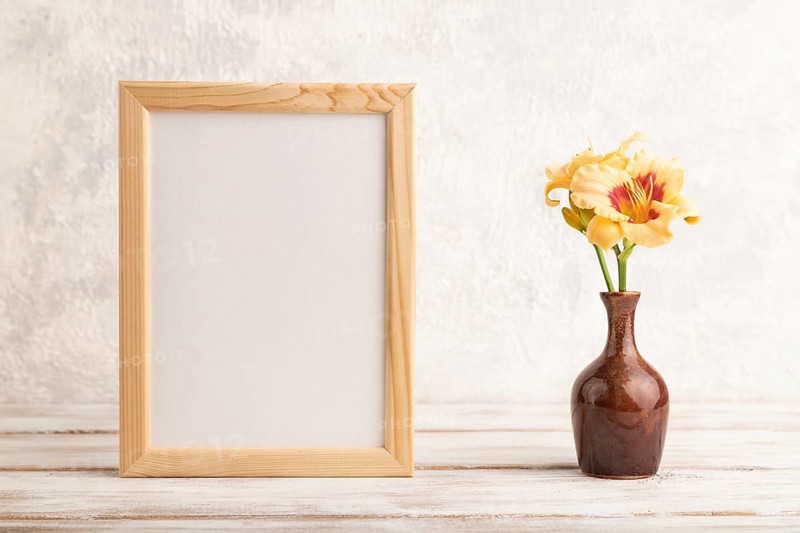 Wooden frame with orange day-lily flowers in ceramic vase on gray concrete background. side view, copy space, still life, mockup, template, spring, summer concept