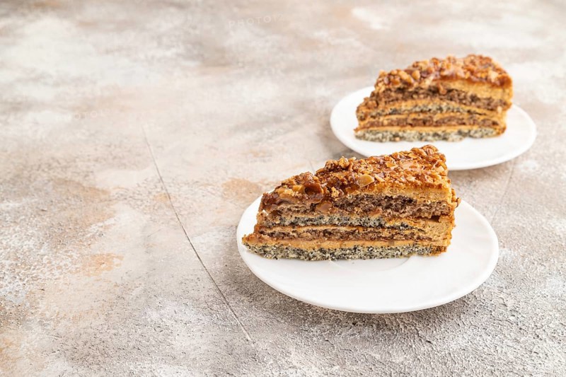 Walnut and hazelnut cake with caramel cream on brown concrete background. side view, copy space