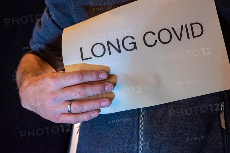 Man holding paper with Long Covid lettering in front of him, studio shot, Germany, Europe