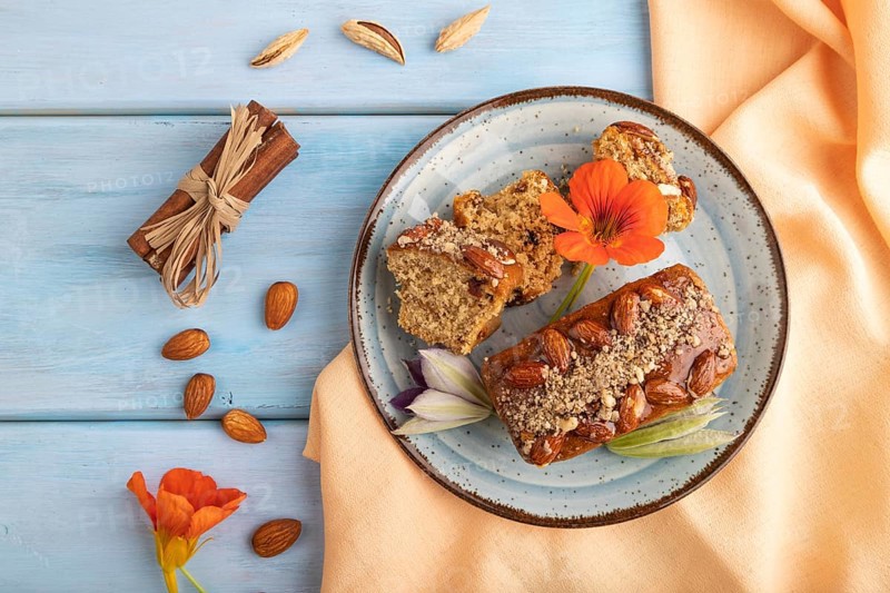 Caramel and almond cake with cup of coffee on blue wooden background and orange linen textile. top view, flat lay, close up