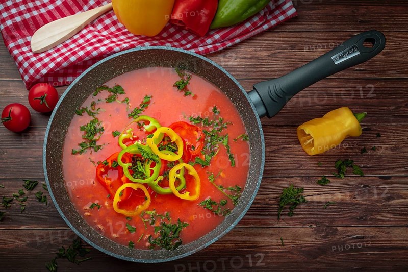 Bean soup with peppers in a pan, served with fresh herbs