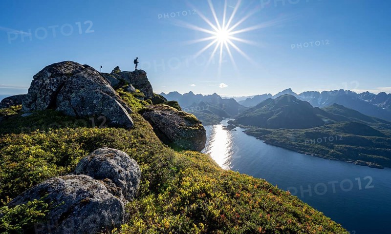 Mountaineer on the summit of Dronningsvarden or Stortinden, behind sea and fjord Umvagsundet, Sonnenstern, Vesteralen, Norway, Europe
