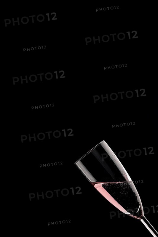 A champagne glass filled with rose sparkling wine against a black background