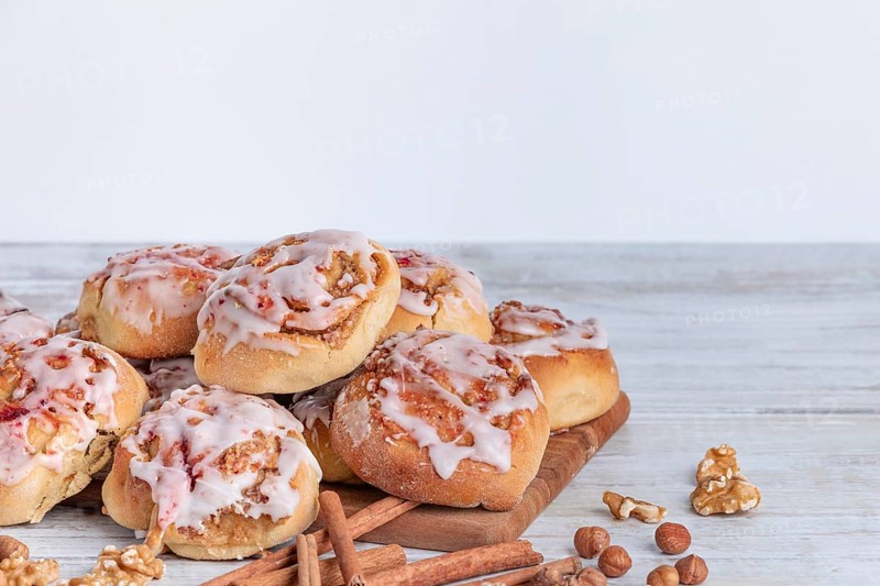 Delicious cinnamon biscuits with nuts and icing on a wooden base