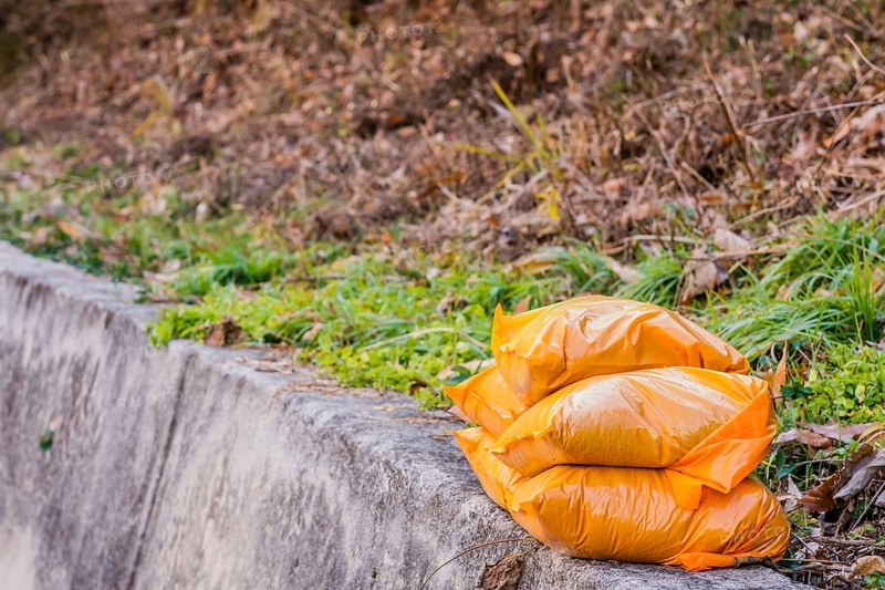 Orange bags of sand stacked on curb of mountain roadside