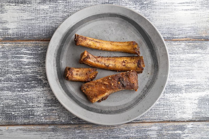 Pork ribs on a wooden plate on a gray wooden background. Top view, flat lay, close up