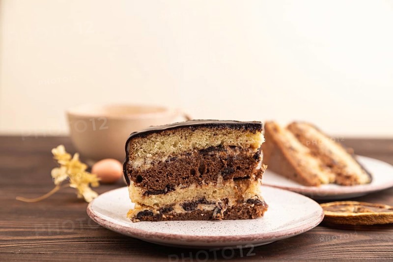 Chocolate biscuit cake with caramel cream, cup of coffee on brown wooden background. side view, close up, selective focus, copy space