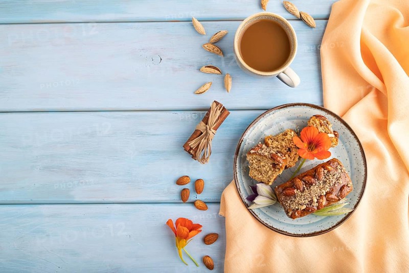 Caramel and almond cake with cup of coffee on blue wooden background and orange linen textile. top view, flat lay, copy space