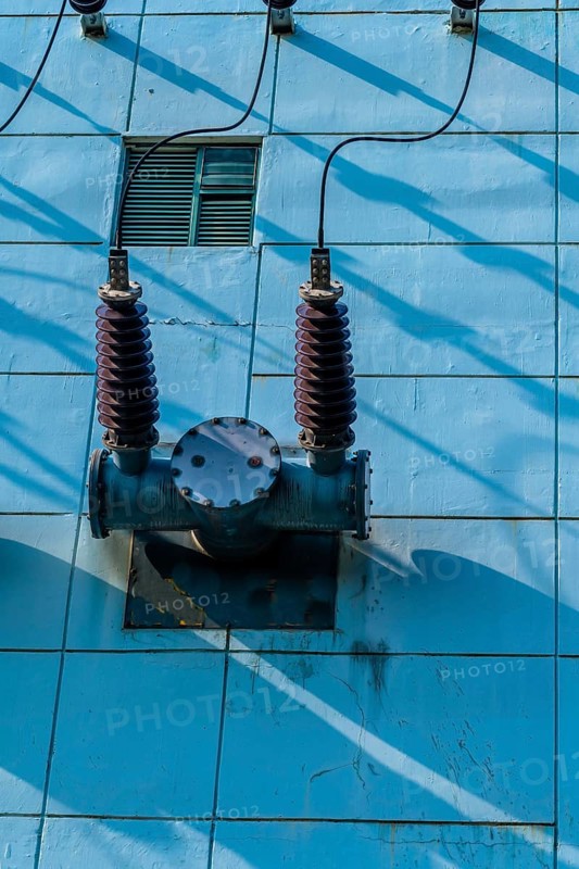 High voltage power lines with ceramic insulators on side of power transfer station building