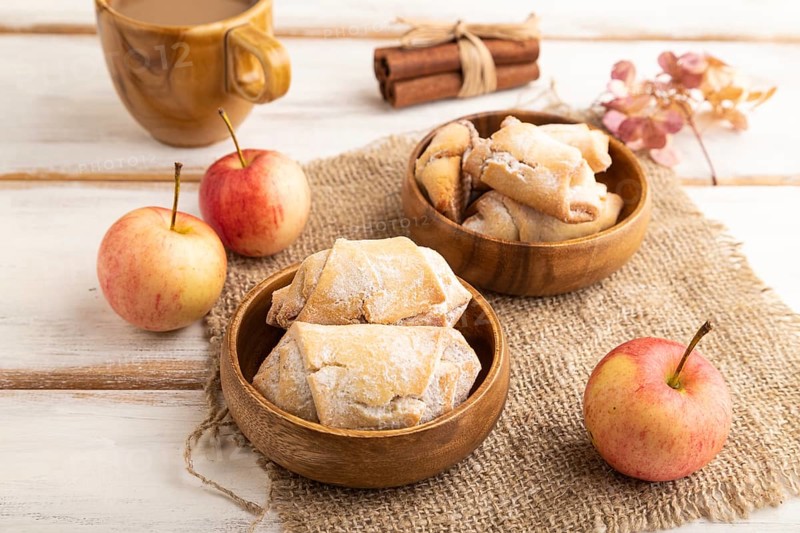 Homemade sweet cookie with apple jam and cup of coffee on white wooden background and linen textile. side view, close up