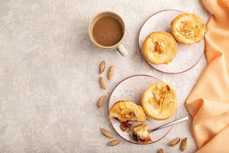 Traditional portuguese cakes pasteis de nata, custard small pies with almonds with cup of coffee on gray concrete background and orange textile. Top view, flat lay, copy space