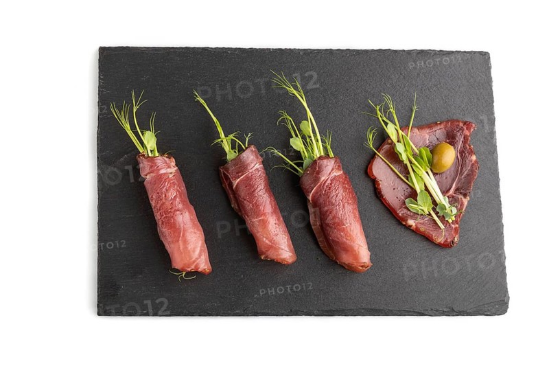 Slices of smoked salted meat with green pea microgreen isolated on white background. Top view, flat lay, close up