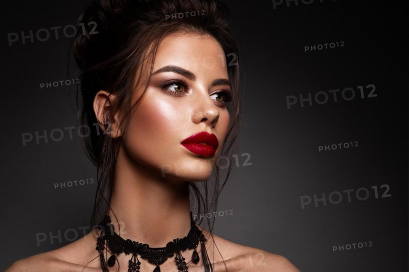 Gorgeous Young Brunette Woman face portrait. Beauty Model Girl with bright eyebrows, perfect make-up, red lips, touching her face. Sexy lady makeup for party