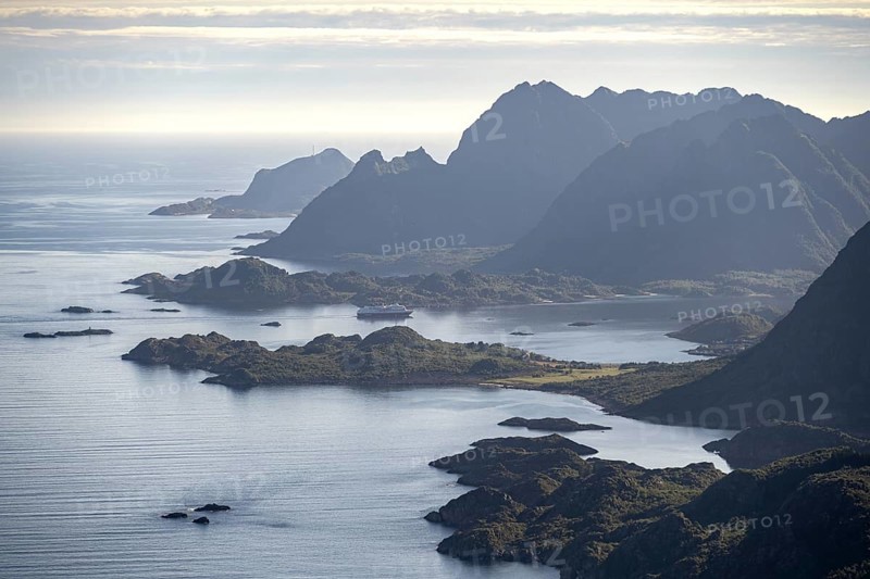 View of the coast in Ulvagsundet fjord and mountains in the evening light, Hurtigruten cruise ship in the fjord, view from the summit of Dronningsvarden or Stortinden, Vesteralen, Norway, Europe