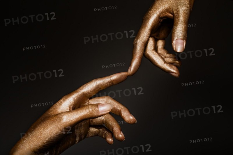Beautiful man's hands in golden paint on black background close up