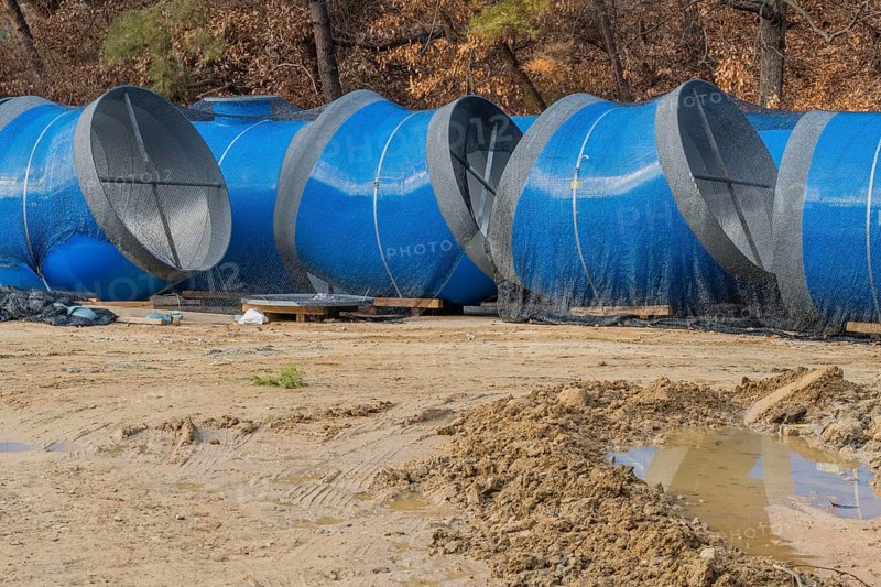 Large blue sections of steel industrial pipes sitting at construction site