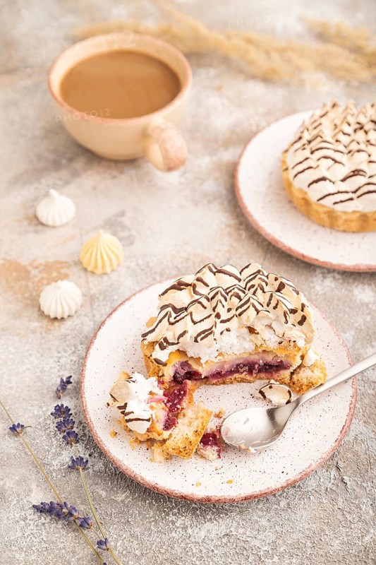 Two tartlets with meringue cream and cup of coffee on brown concrete background. side view, selective focus. Breakfast, morning, concept