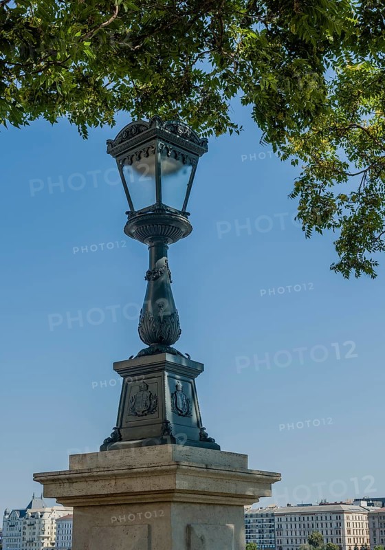 Ornate vintage street lamp against a clear blue sky in a city setting