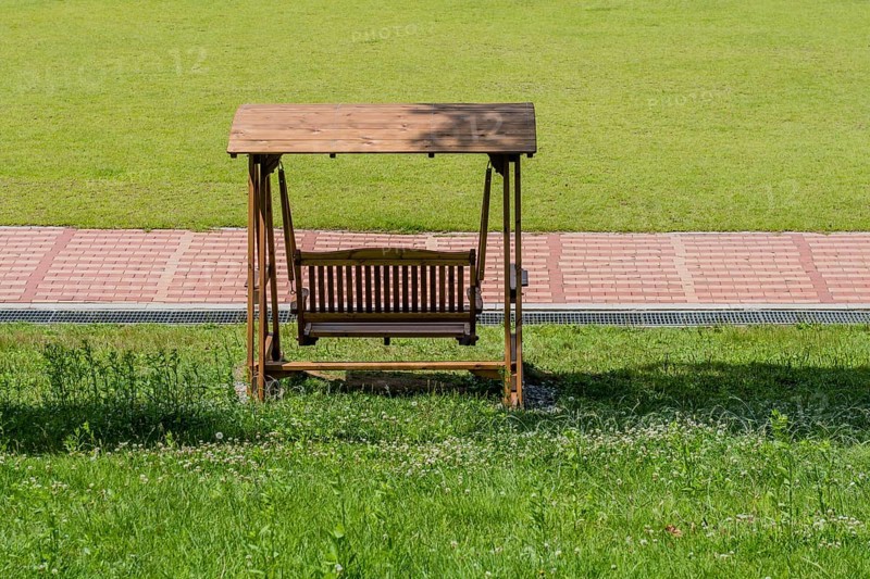 Rear view of wooden swing park bench beside walkway in South Korea