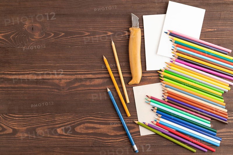 Set of watercolor pencils on brown wooden background. Top view, flat lay, copy space