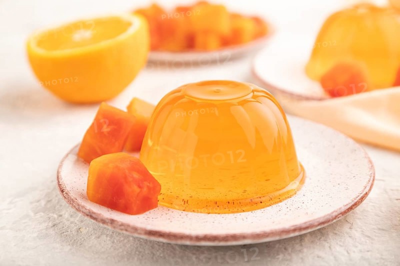 Papaya and orange jelly on gray concrete background and orange linen textile. side view, flat lay, close up, selective focus