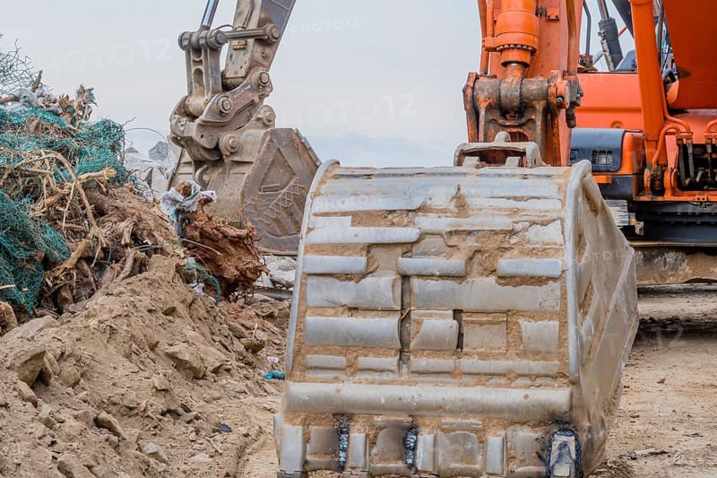Closeup of bucked on backhoe parked at rural construction site on overcast day