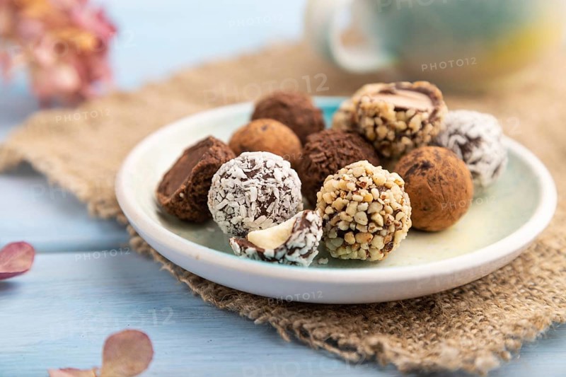 Chocolate truffle candies with cup of coffee on a blue wooden background and linen textile. side view, close up, selective focus