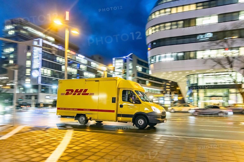 Vehicle of the parcel service provider DHL, modern architecture in the evening, motion blur, Stuttgart, Baden-Württemberg, Germany, Europe