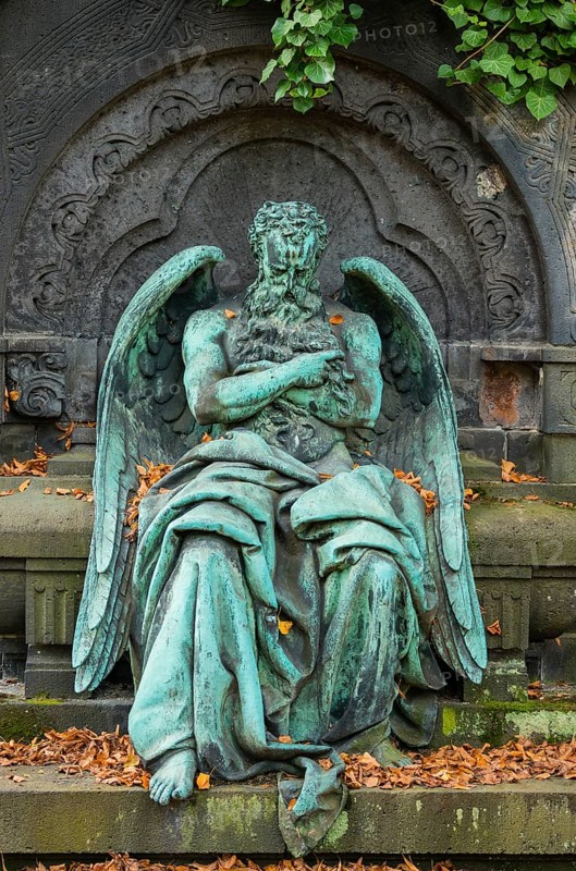 Historic angel figurine, angel figure, angel figurine, male angel statue with full beard, bronze with verdigris, surrounded by autumn leaves, grave monument, mourning, condolence, death, transience, cemeteries on Bergmannstraße, Berlin-Kreuzberg, Berlin, Germany, Europe