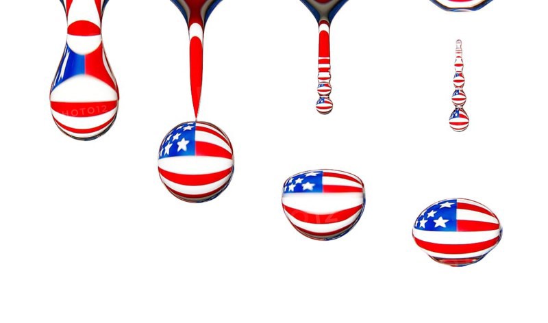 Macro shot of a drop of water dripping, the national flag of the USA is reflected in the drop