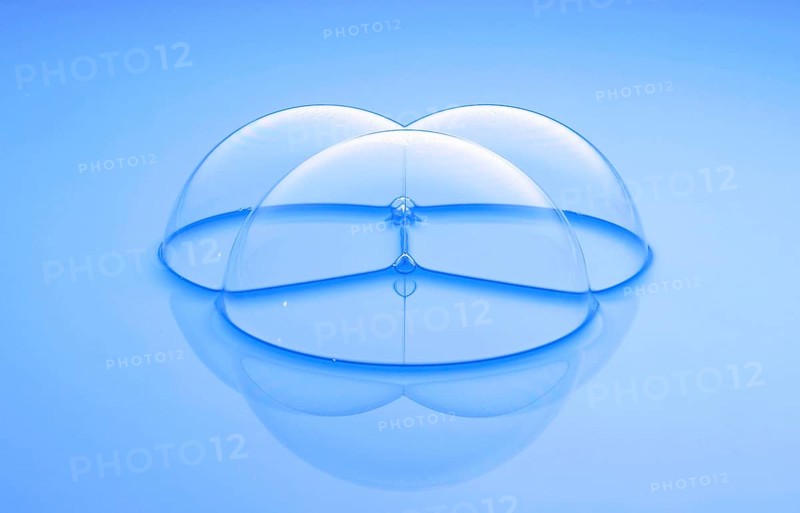 Three large soap bubbles on light blue water