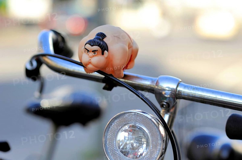 A sumo wrestler attached to the handlebars of a bicycle as a bicycle horn or bell