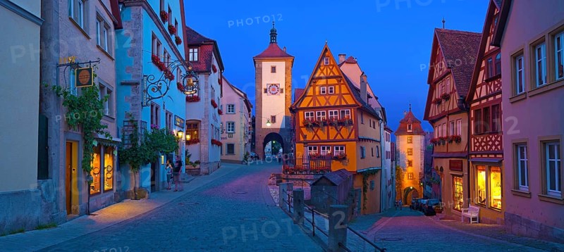 Town view of Rothenburg ob der Tauber in the evening at blue hour, in the foreground the Plönlein Platz, the Kobolzell tower on the right and the Siebersturm on the left, people are unrecognizable, Bavaria, Germany, Europe