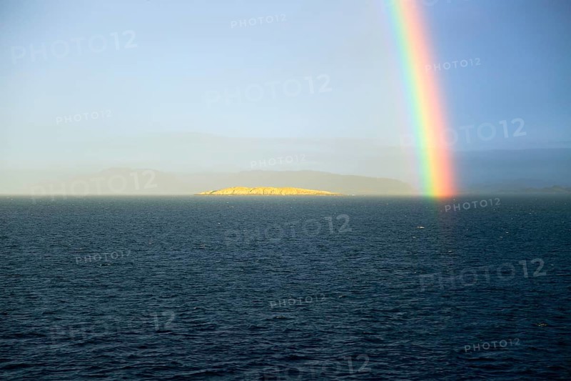Seascape view of spectrum colours in rainbow over sea and island, Norway, Europe