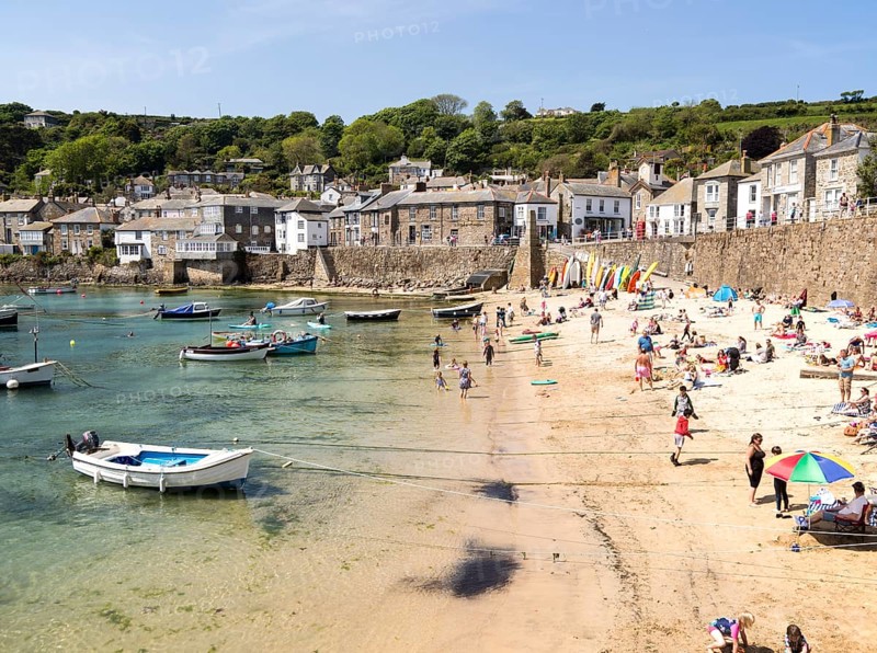 People on crowded beach in Mousehole village, Cornwall, England, UK