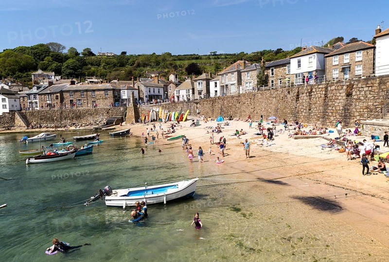 People on crowded beach in Mousehole village, Cornwall, England, UK