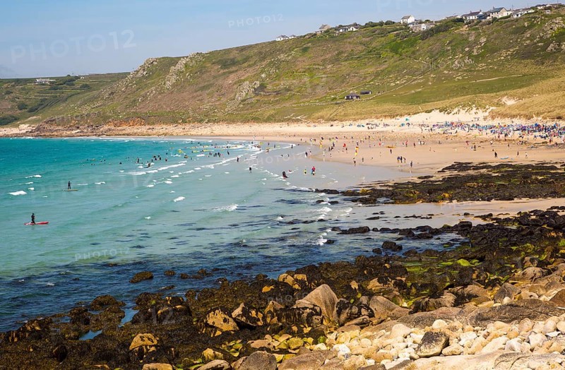 Coastal scenery with busy crowded sandy beach, Sennan Cove, Land's End, Cornwall, England, UK
