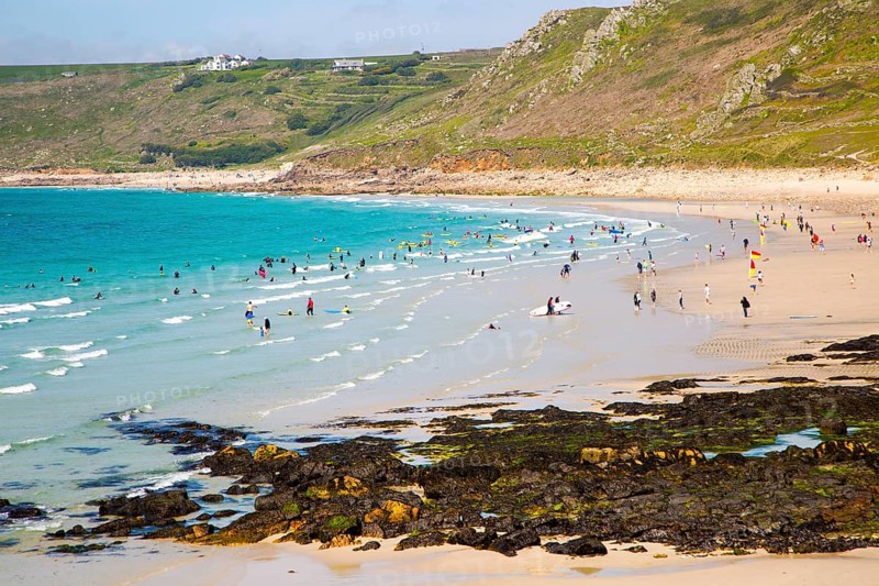 Coastal scenery with busy crowded sandy beach, Sennan Cove, Land's End, Cornwall, England, UK