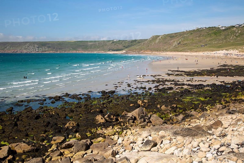Coastal scenery with busy crowded sandy beach, Sennan Cove, Land's End, Cornwall, England, UK