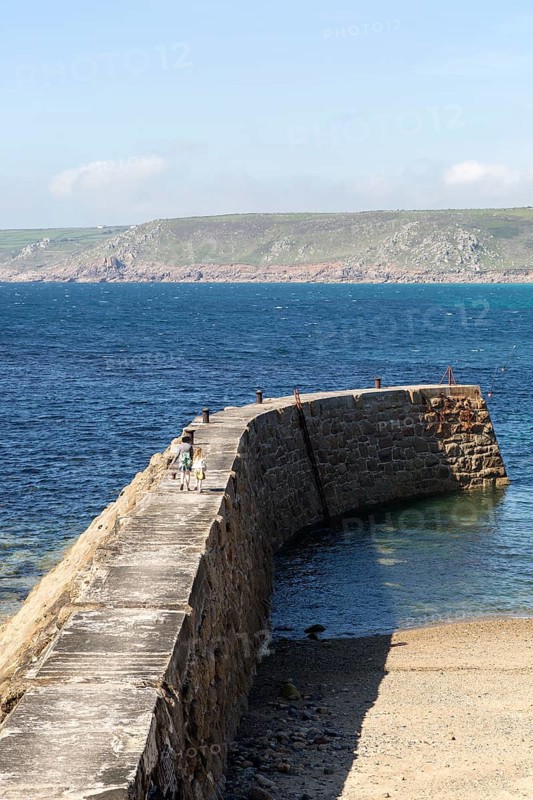 Woman and girl walking on breakwater quay, Sennen Cove, Land's End, Cornwall, England, UK