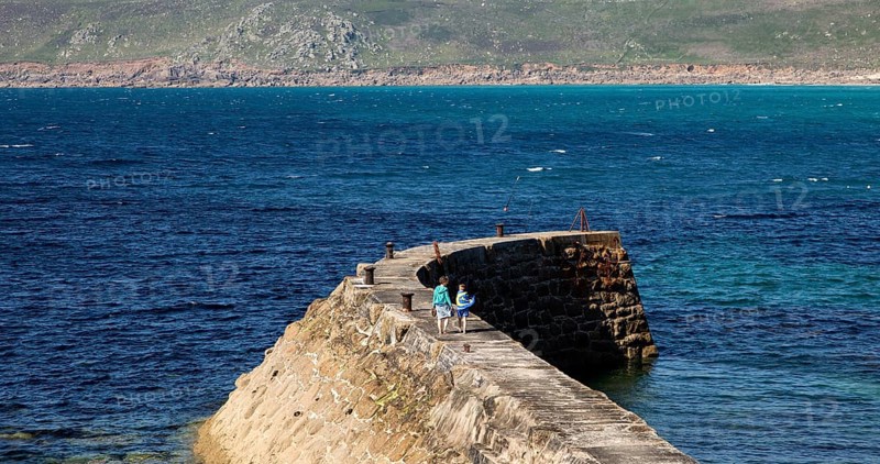Woman and girl walking on breakwater quay, Sennen Cove, Land's End, Cornwall, England, UK