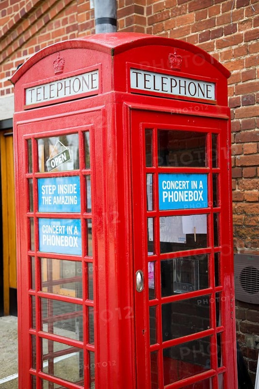 Concert in a Phonebox in old red traditional phone box booth, Snape Maltings, Suffolk, England, UK