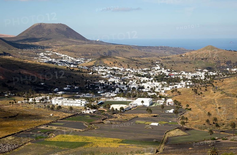 View over cactus plants and whitewashed houses to Monte Corona volcano cone, village of Haria, Lanzarote, Canary Islands, Spain, Europe
