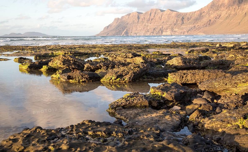 Late afternoon light on beach and cliffs La Caleta de Famara, Lanzarote, Canary islands, Spain, Europe