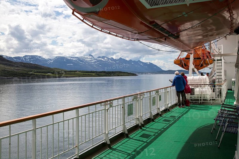 Two people on deck viewing scenery on Hurtigruten ferry ship, near the Arctic Circle crossing, Norway, Europe